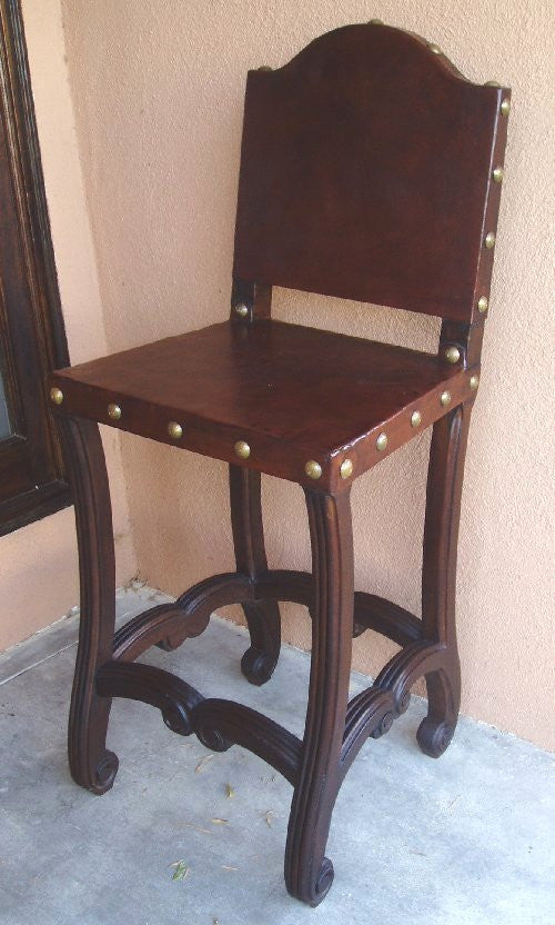 Brown wooden bar chair with leather seat and intricate woodcarvings on the legs.